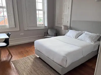 a bedroom with a large white bed and a chair at Porto Republica Ribeira in Porto