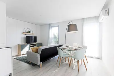 a white living room with a table and a couch at Stylish Flat W/ Gym & Parking by LovelyStay in Porto