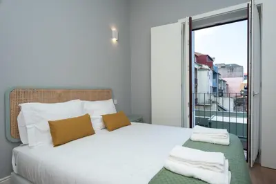 a bedroom with a white bed and a balcony at Porto XL in Porto