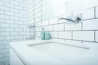 a white tiled bathroom with a white sink at Porto XL in Porto