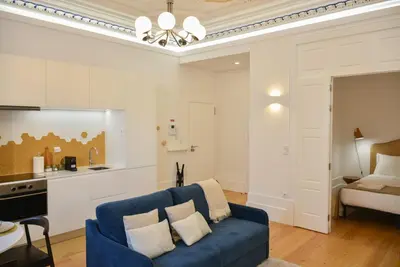 a living room with a blue couch and a kitchen at Apartamento encantador na Batalha - Porto - APT E in Porto