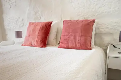 a white bed with two red pillows on it at Entire House with 4 Master Suites, Hot Tub & Backyard - Central Location in Vila Nova de Gaia
