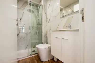 a white bathroom with a shower and a toilet at Entire House with 4 Master Suites, Hot Tub & Backyard - Central Location in Vila Nova de Gaia