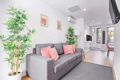 a living room with a gray couch with pink pillows at Entire House with 4 Master Suites, Hot Tub & Backyard - Central Location in Vila Nova de Gaia