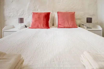 a white bed with two red pillows on it at Entire House with 4 Master Suites, Hot Tub & Backyard - Central Location in Vila Nova de Gaia