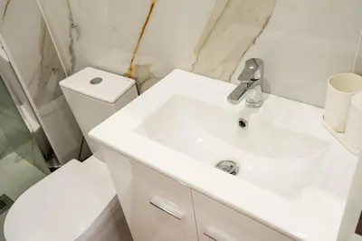 a white bathroom with a sink and a toilet at Entire House with 4 Master Suites, Hot Tub & Backyard - Central Location in Vila Nova de Gaia