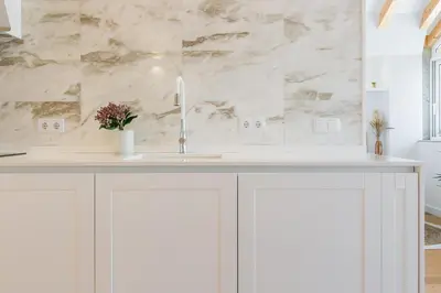 a white kitchen with a sink and a marble wall at ORM Prado Apartment in Porto