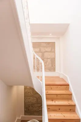 a white staircase in a house with wooden floors at ORM Prado Apartment in Porto