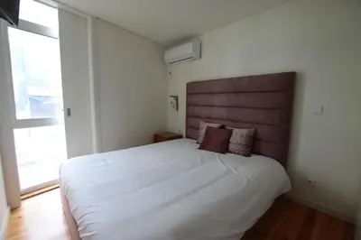 a bedroom with a large white bed and a large window at OPORTO GUEST Natária Flats with Parking in Porto