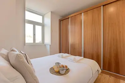 a bedroom with a large white bed with a wooden cabinet at Monte dos Judeus 26 by LovelyStay in Porto