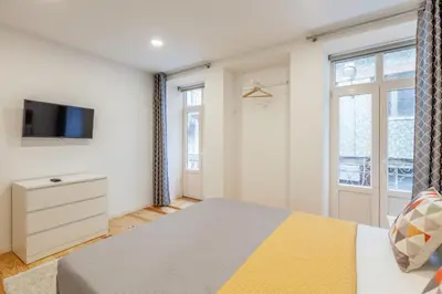 a bedroom with a bed and a tv on a wall at Villa Apartments & Suites in Porto