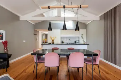 a dining room with a black table and pink chairs at The Mouzinho Penthouse in Porto