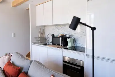 a kitchen with white cabinets and a couch and a microwave at Casa Girasol River View in Porto