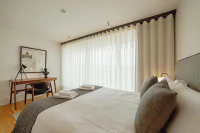 a bedroom with a bed with a desk and a window at Downtown Penthouse With River View by Vacationy in Porto