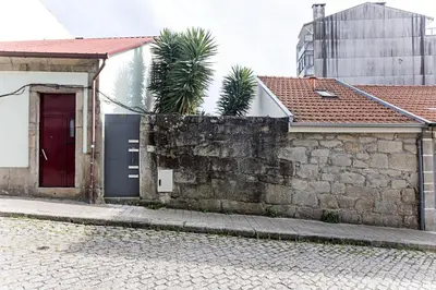 a brick building with a red door and a stone wall at Cozy House w/ AC near metro by LovelyStay in Porto