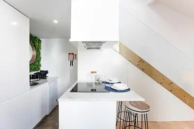 a white kitchen with white cabinets and a staircase at Cozy House w/ AC near metro by LovelyStay in Porto