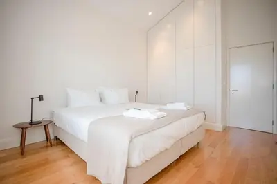 a white bedroom with a large white bed and a table at Liiiving in Gaia - Douro Dream View in Vila Nova de Gaia