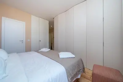 a bedroom with a white bed and a chair at Firmeza Apartment by Amber Star Rent in Porto