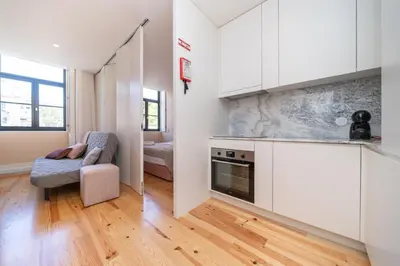 a kitchen with white cabinets and a chair in a room at Firmeza Apartment by Amber Star Rent in Porto