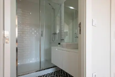 a bathroom with a glass shower and a sink at Oporto Rooftop Studio by Vacationy in Porto