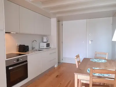 a kitchen with white cabinets and a table with chairs at Porto Vista by Flat in Porto in Porto