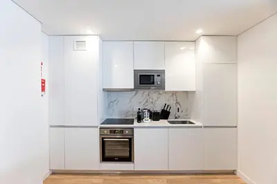 a white kitchen with a stove and a microwave at Paraíso -1B w/ AC & Patio by LovelyStay in Porto