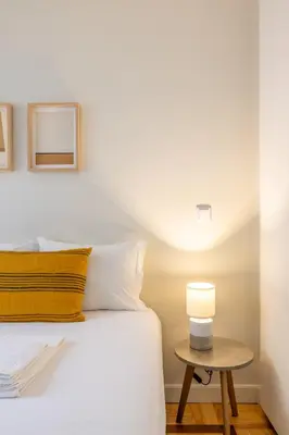 a bedroom with a bed and a table with a lamp at Casa do Ofício Galerista in Porto