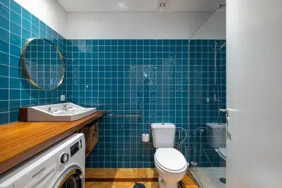 a blue tiled bathroom with a toilet and a sink at Casa do Ofício Galerista in Porto
