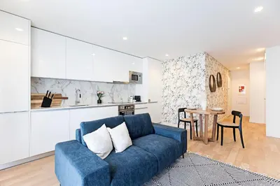 a living room with a blue couch and a kitchen at NEW Cozy and Modern Apartment in the heart of Porto in Porto