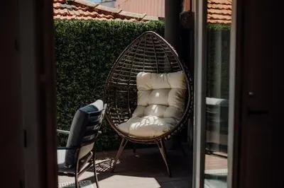 a wicker chair with pillows sitting on a patio at Green Garden Luxury House w/ AC, Metro & Downtown in Porto