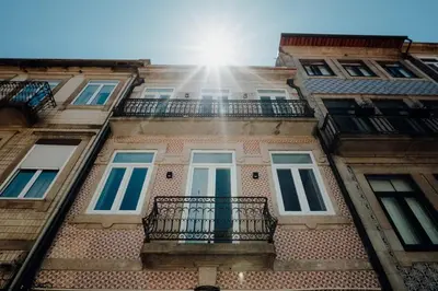 a building with a balcony and the sun in the sky at Green Garden Luxury House w/ AC, Metro & Downtown in Porto