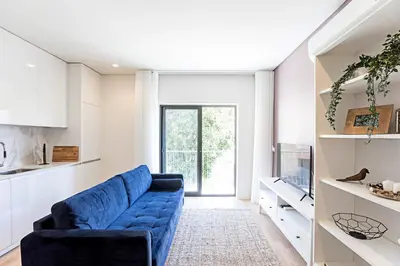 a living room with a blue couch and a tv at Paraíso 1H w/ AC by LovelyStay in Porto