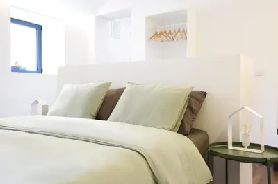 a white bedroom with a bed and a side table at Alegria Cool House in Porto