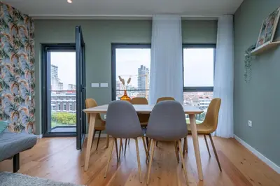 a dining room with a table and chairs and windows at Trindade Duplex by Amber Star Rent in Porto