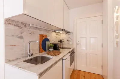 a white kitchen with a sink and a door at D&S -JB Apartments in Porto