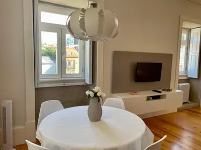 a dining room with a table and a vase with flowers at Santo António Elegant Flat in Porto