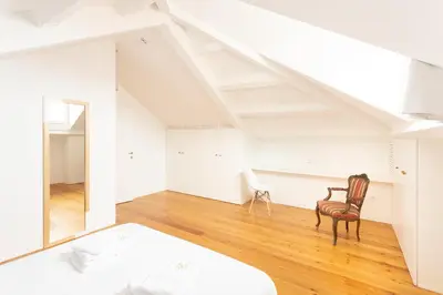 a bedroom with a bed and a chair in a attic at Apartamentos da Capela in Porto