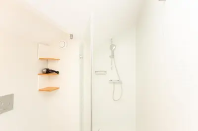 a shower in a white bathroom with a glass door at Apartamentos da Capela in Porto