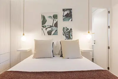 a bedroom with a bed with white sheets and pillows at Wonderful 2BR Duplex Near River by LovelyStay in Porto