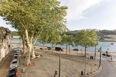 a street with cars parked next to a river at Wonderful 2BR Duplex Near River by LovelyStay in Porto