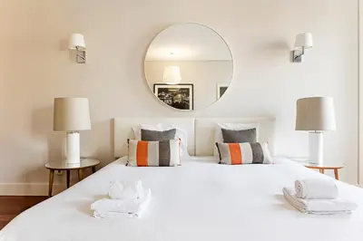 a bedroom with a large white bed with a mirror at Palácio das Cardosas Studio by LovelyStay in Porto