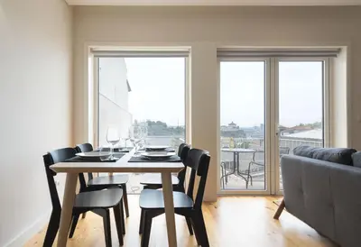 a dining room with a table and chairs and a couch at BmyGuest - São Vitor Balcony Apartment in Porto