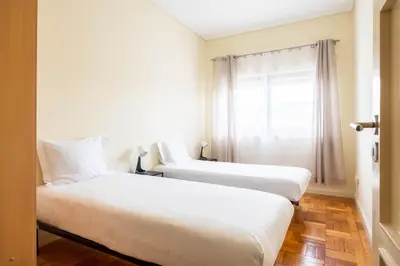two beds in a hotel room with a window at Convenient 3-Bedroom Apartments next to Bom Sucesso in Porto