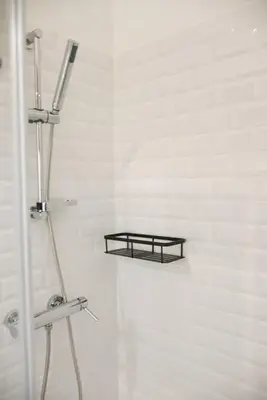 a shower with a black shelf in a bathroom at Comfort next to main avenue and metro Trindade in Porto