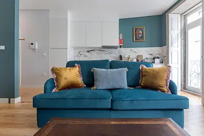 a blue couch with pillows in a living room at Turquoise Central Flat w AC & Balcony by LovelyStay in Porto