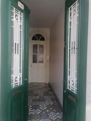 a hallway with green doors and a tile floor at HOSPEDARIA LONDRES in Porto