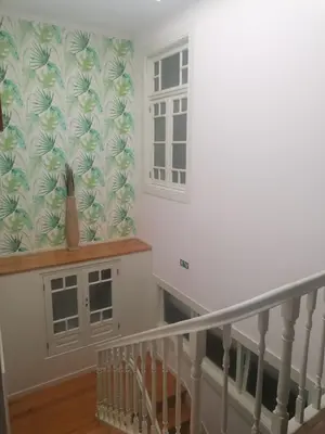 a hallway with a staircase with a window and a curtain at HOSPEDARIA LONDRES in Porto