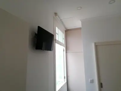 a room with a tv on the wall next to a window at HOSPEDARIA LONDRES in Porto