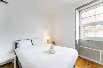 a white bed in a room with a window at GuestReady - Modern Duplex, Neo-Classical Building in Porto