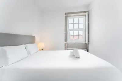 a white bed in a white room with a window at GuestReady - Modern Duplex, Neo-Classical Building in Porto